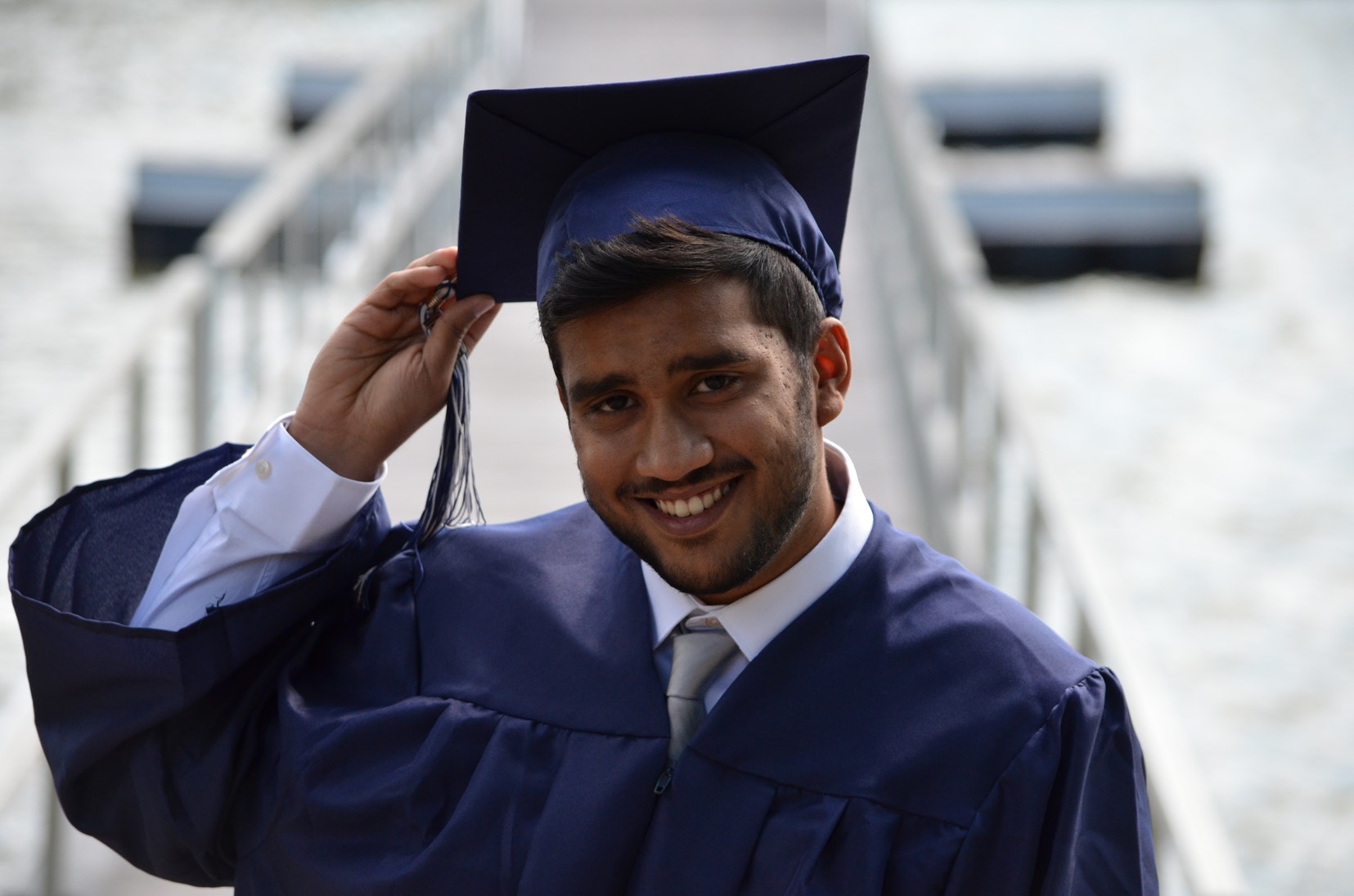 A student in his graduation gown holding his graduation hat.