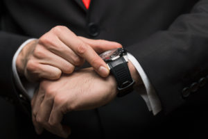 An Impact Trailblazer image of a business man holding his watch.