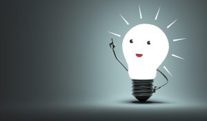 Lightbulb glowing white with cartoon facial features and a metallic arm pointing upright; this is symbolic of innovation and ideas. Business Impact article from Leading change and inspiring lifelong learning.
