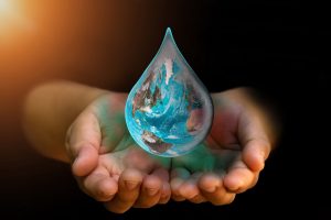 Hands cupping the earth that is shaped like a giant water droplet. Adding drops to the ocean of change.