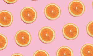 A fruitful pattern of cut oranges on a baby pink background.