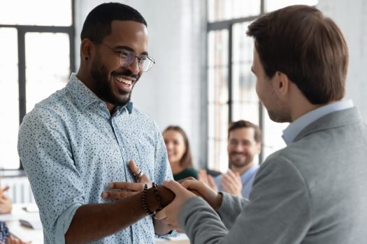 Caucasian businessman handshake African American male employee congratulate with work achievement or success, boss shake hand of biracial worker greeting with job promotion at office meeting. Excellence Awards, BGA Student of the Year Award.