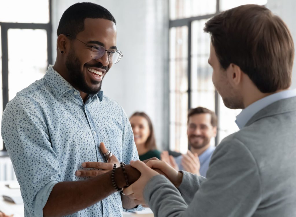 Caucasian businessman handshake African American male employee congratulate with work achievement or success, boss shake hand of biracial worker greeting with job promotion at office meeting. Excellence Awards, BGA Student of the Year Award.