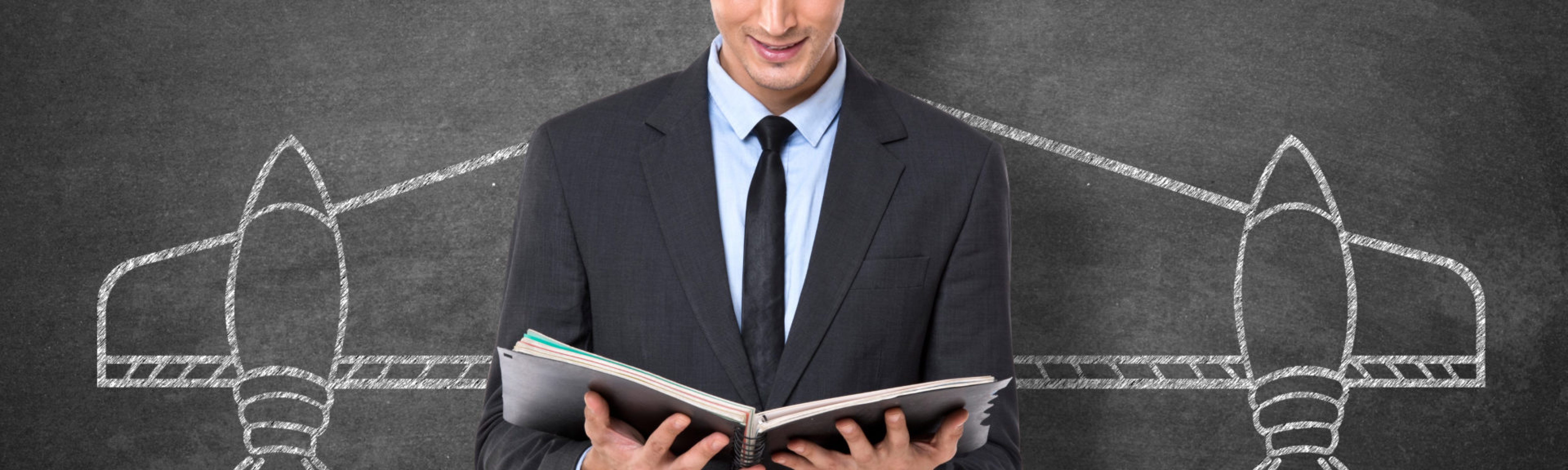Businessman holding diary in front blackboard