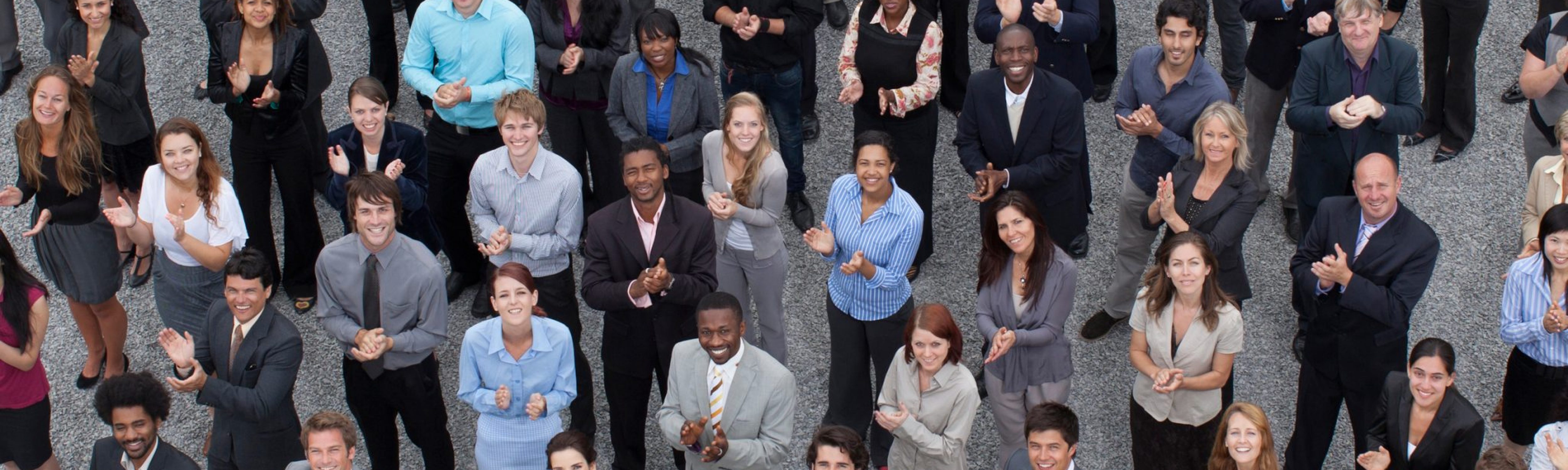 Here is a large, diverse crowd of business working professionals socially distancing standing outside dressed in smart attire. Business Impact article for A brighter future: culture, diversity and inclusion.